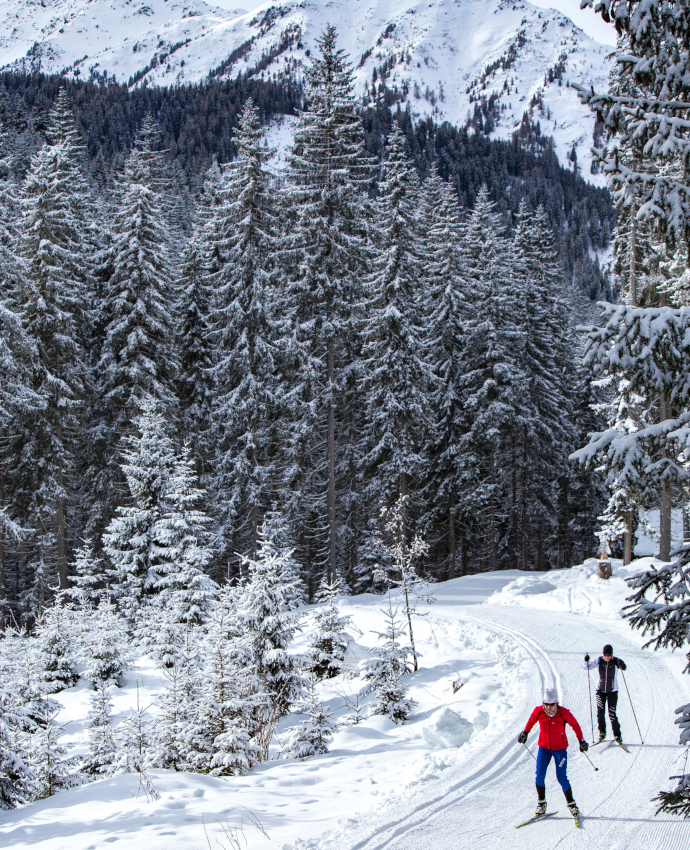Langlaufen durch verschneite Waldabschnitte in Tirol